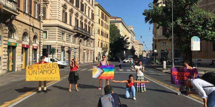 Attivistə in cerchio con tamburelli e bandiera queer danzano in ricordo dei Moti di Stonewall