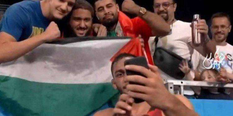 L’atleta iraniano Azar Pira vince la medaglia di bronzo di lotta libera e scatta selfie con bandiera palestinese